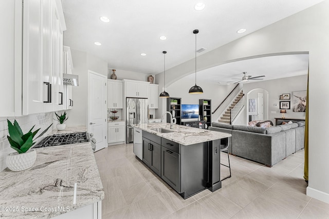 kitchen featuring sink, white cabinetry, appliances with stainless steel finishes, pendant lighting, and a kitchen island with sink