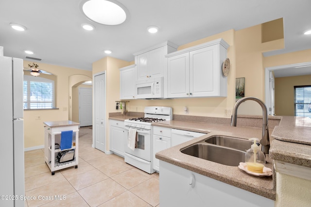 kitchen featuring sink, light tile patterned floors, kitchen peninsula, white appliances, and white cabinets