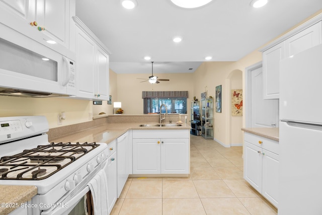 kitchen with white appliances, kitchen peninsula, sink, and white cabinets