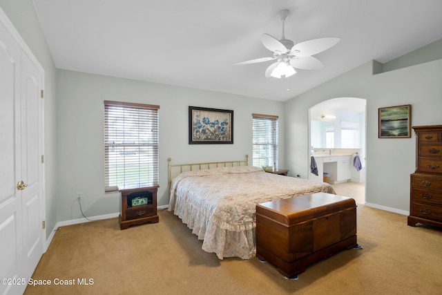 bedroom featuring lofted ceiling, ceiling fan, light carpet, ensuite bath, and a closet