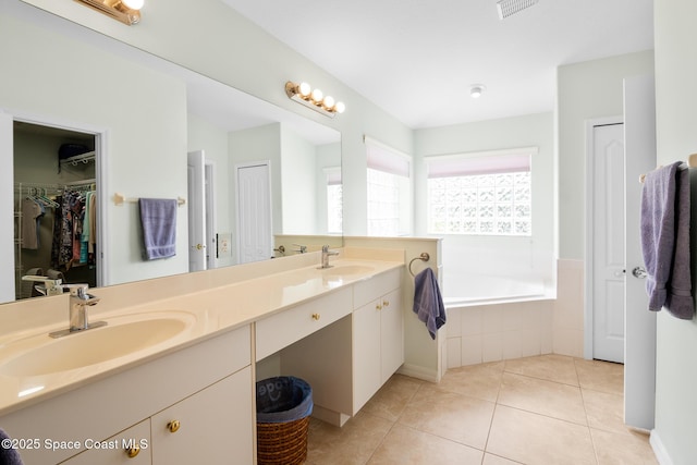 bathroom featuring tile patterned flooring, tiled tub, and vanity