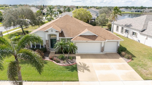 view of front facade featuring a garage, a front lawn, and a water view