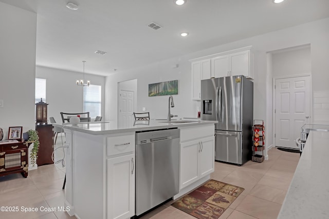 kitchen with stainless steel appliances, white cabinetry, sink, and a center island with sink