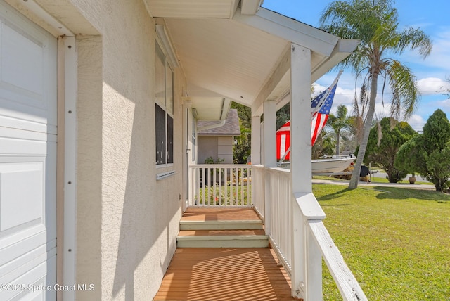 exterior space featuring a porch, a lawn, and stucco siding