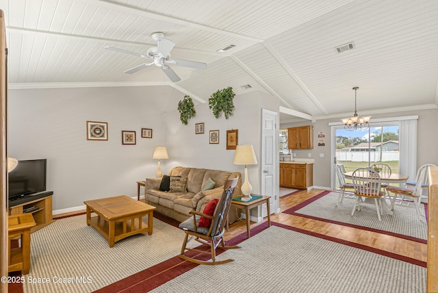 living area with lofted ceiling, ceiling fan with notable chandelier, visible vents, ornamental molding, and light wood-type flooring