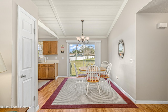 dining area with a chandelier, crown molding, light wood-style flooring, and baseboards