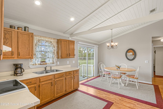 kitchen featuring visible vents, vaulted ceiling with beams, light countertops, pendant lighting, and a sink