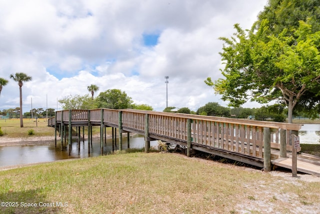 view of dock featuring a lawn and a water view