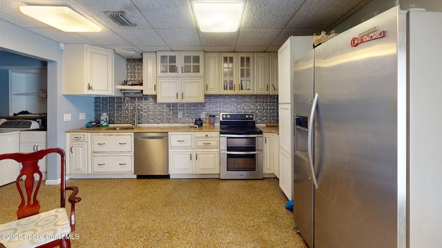 kitchen featuring stainless steel appliances, sink, washer and dryer, and white cabinets