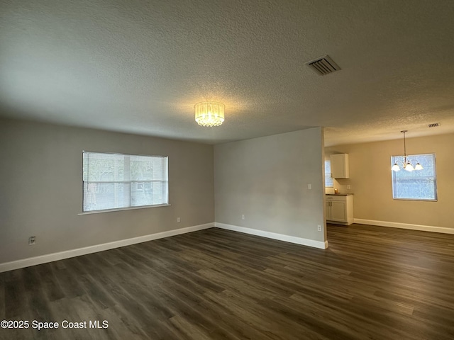 spare room with dark hardwood / wood-style floors, a chandelier, and a wealth of natural light