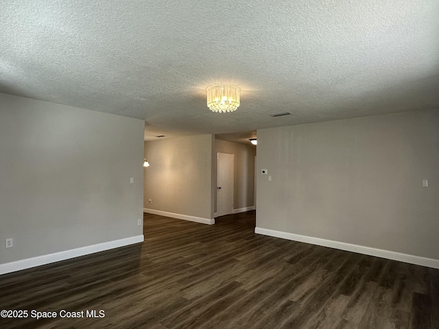 spare room featuring dark hardwood / wood-style floors and a textured ceiling