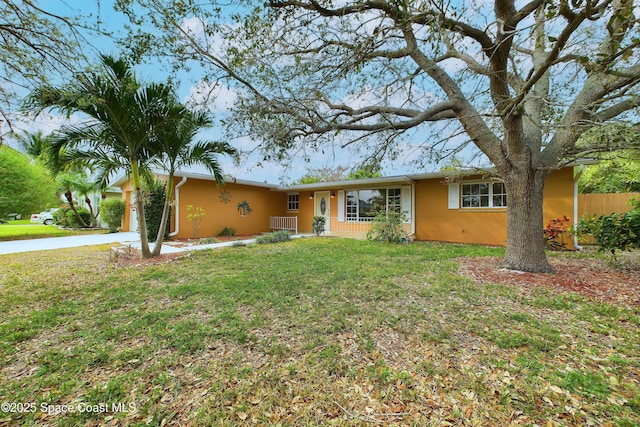 ranch-style home featuring an attached garage, fence, a front lawn, stucco siding, and driveway