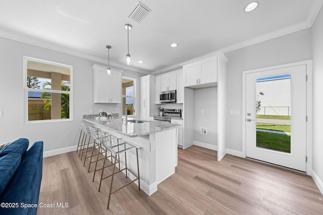 kitchen with a breakfast bar area, white cabinetry, decorative light fixtures, stainless steel appliances, and light stone countertops