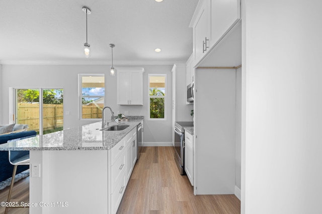 kitchen featuring sink, white cabinetry, light stone counters, decorative light fixtures, and appliances with stainless steel finishes