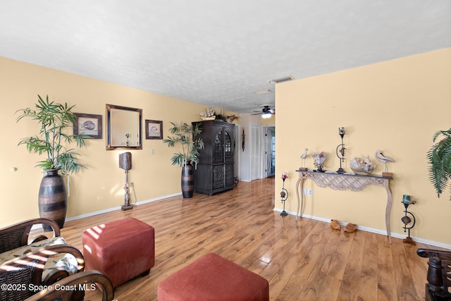 living room featuring wood-type flooring, a textured ceiling, and ceiling fan