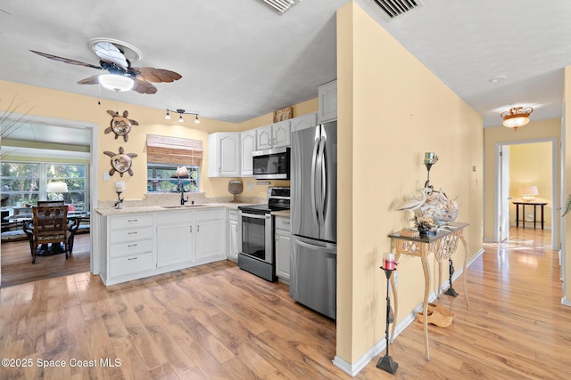 kitchen featuring sink, ceiling fan, stainless steel appliances, white cabinets, and light wood-type flooring