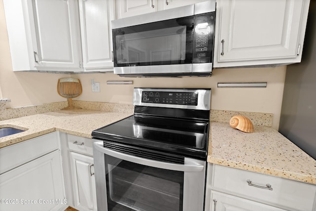 kitchen featuring appliances with stainless steel finishes, white cabinets, and light stone counters