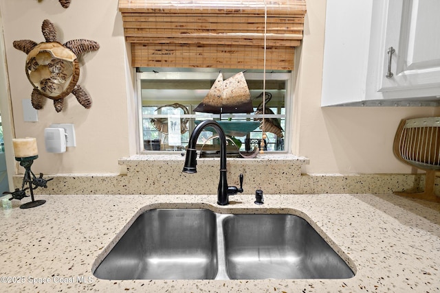 details featuring light stone counters, sink, and white cabinets