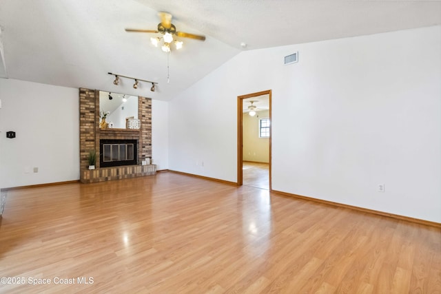 unfurnished living room featuring ceiling fan, lofted ceiling, a brick fireplace, and light hardwood / wood-style flooring