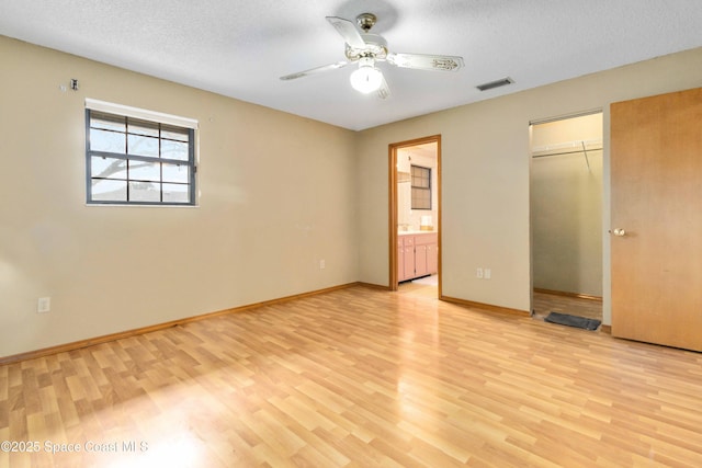 unfurnished bedroom with ceiling fan, ensuite bathroom, light hardwood / wood-style floors, and a textured ceiling