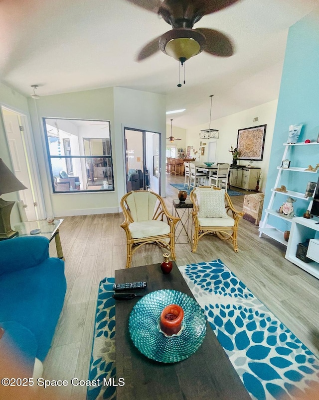 living room with light hardwood / wood-style flooring, ceiling fan, and vaulted ceiling