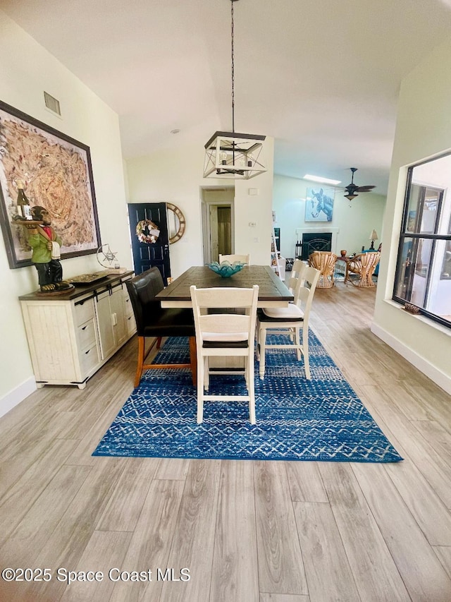 dining space featuring ceiling fan, lofted ceiling, and light wood-type flooring