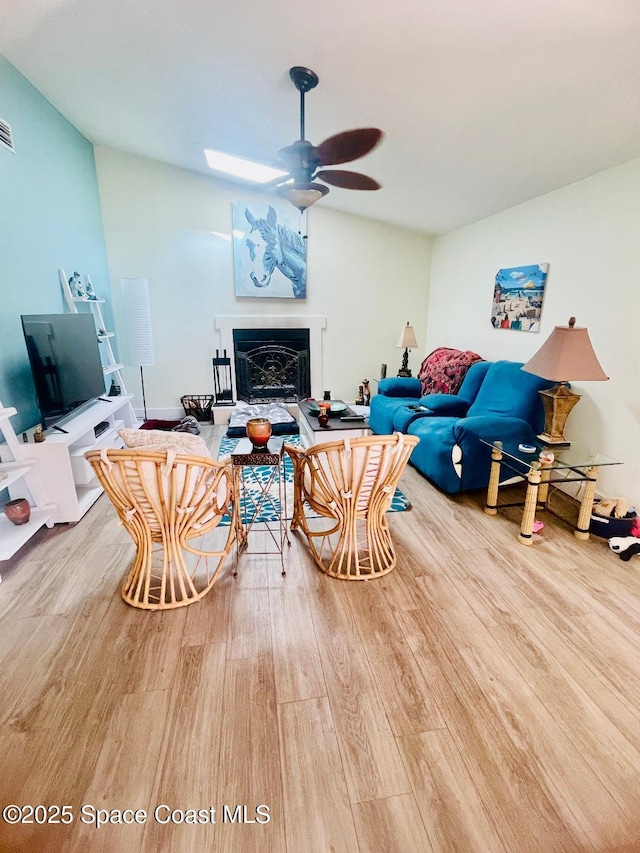 living room featuring wood-type flooring, ceiling fan, and vaulted ceiling