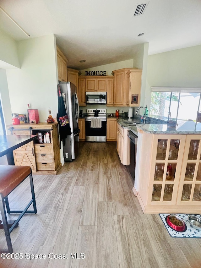 kitchen with light brown cabinetry, sink, appliances with stainless steel finishes, light stone countertops, and light hardwood / wood-style floors