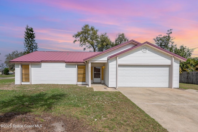 single story home featuring a garage, concrete driveway, metal roof, and a front lawn