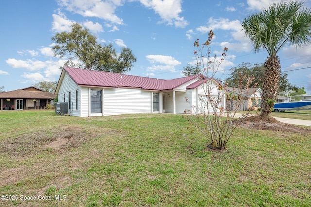 single story home featuring metal roof, central AC unit, a garage, driveway, and a front yard