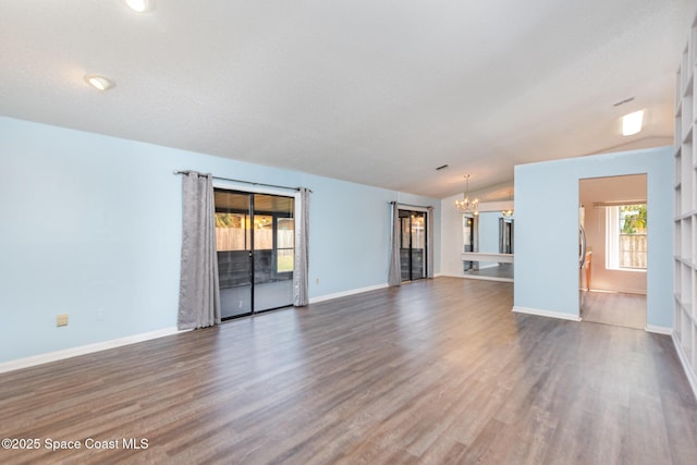 unfurnished living room with baseboards, lofted ceiling, dark wood-style flooring, a textured ceiling, and a notable chandelier