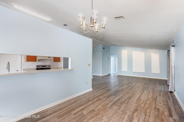 unfurnished living room featuring a chandelier, visible vents, a textured ceiling, and wood finished floors