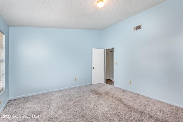 empty room featuring a textured ceiling, carpet, visible vents, and baseboards