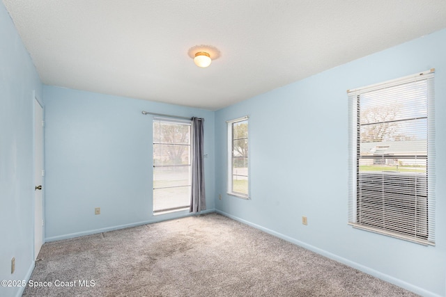 unfurnished room featuring carpet and baseboards