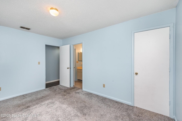 unfurnished bedroom featuring baseboards, visible vents, connected bathroom, a textured ceiling, and carpet floors