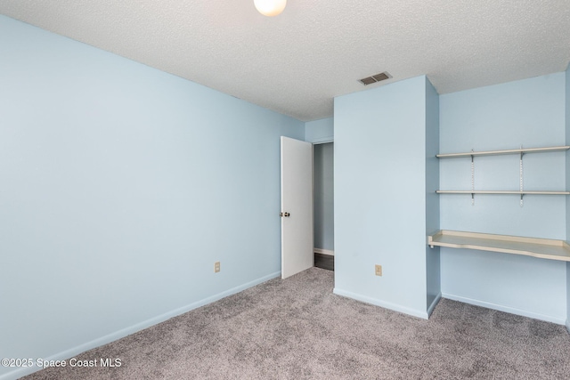 unfurnished bedroom with visible vents, baseboards, a textured ceiling, and light colored carpet