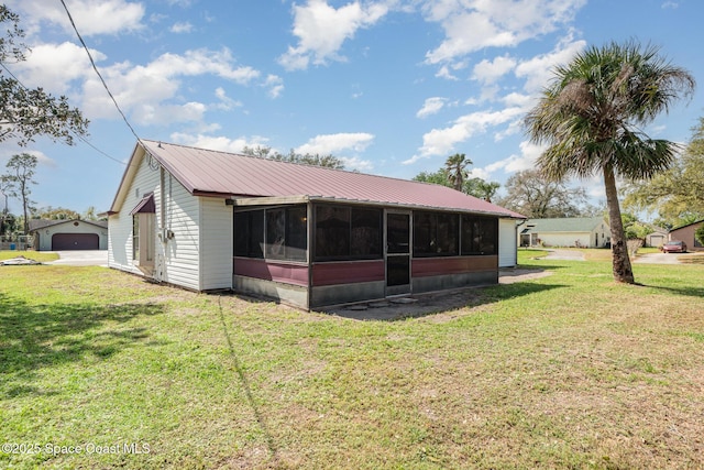 back of property with a sunroom, metal roof, and a lawn