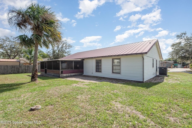 rear view of property featuring a lawn, a sunroom, metal roof, fence, and cooling unit