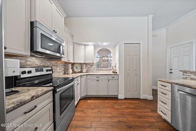 kitchen with dark wood-type flooring, stainless steel appliances, light stone counters, white cabinets, and decorative backsplash