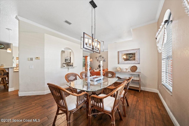 dining room featuring crown molding, dark wood-type flooring, and a chandelier