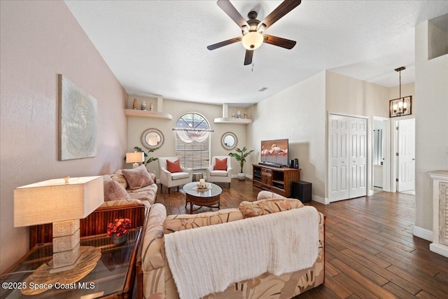 living room featuring dark hardwood / wood-style flooring, ceiling fan with notable chandelier, and a textured ceiling