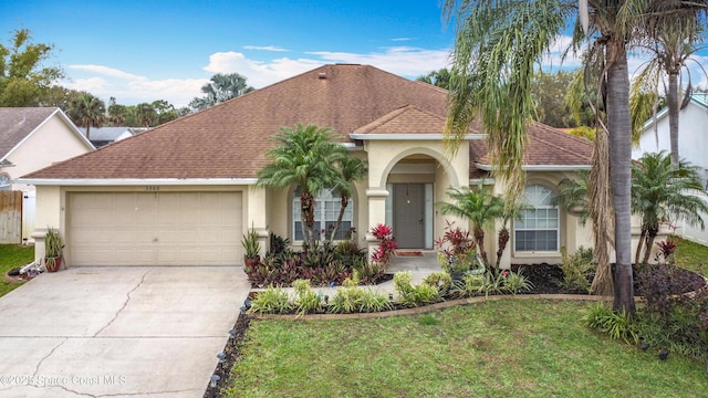 view of front of house with a garage, driveway, a front lawn, and stucco siding