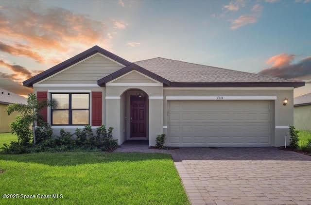 ranch-style home featuring a garage and a lawn