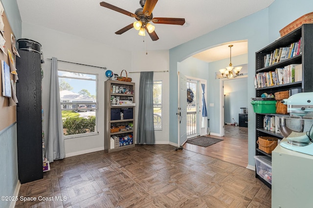 foyer with ceiling fan with notable chandelier, parquet flooring, and a healthy amount of sunlight