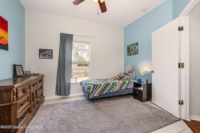 bedroom with ceiling fan, light tile patterned floors, and a textured ceiling