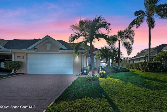 ranch-style home with a garage and a yard