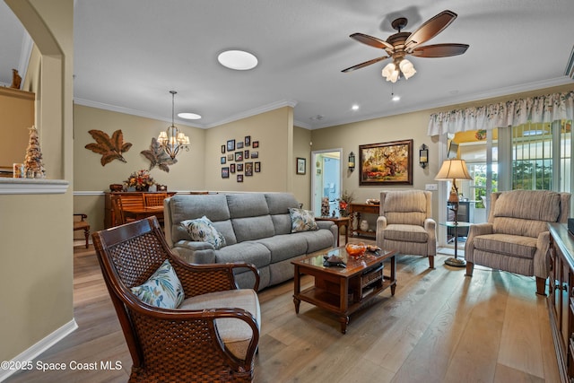 living room with ornamental molding, ceiling fan with notable chandelier, and light hardwood / wood-style floors