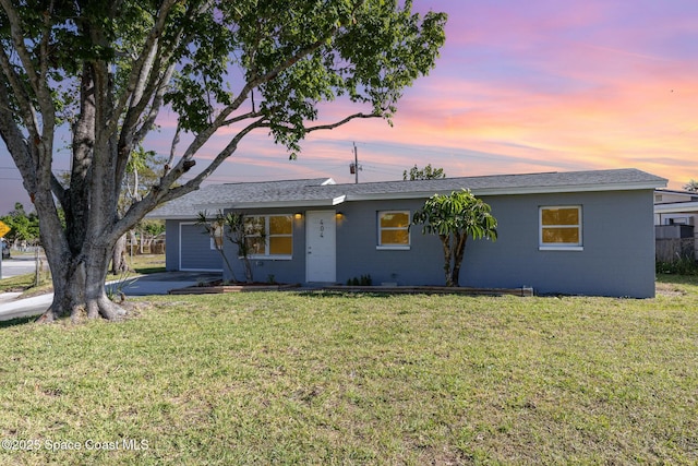 ranch-style home with concrete block siding and a front yard