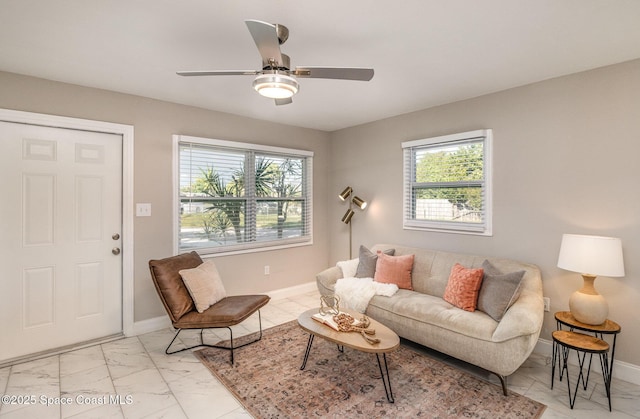 living area featuring baseboards, marble finish floor, and a ceiling fan