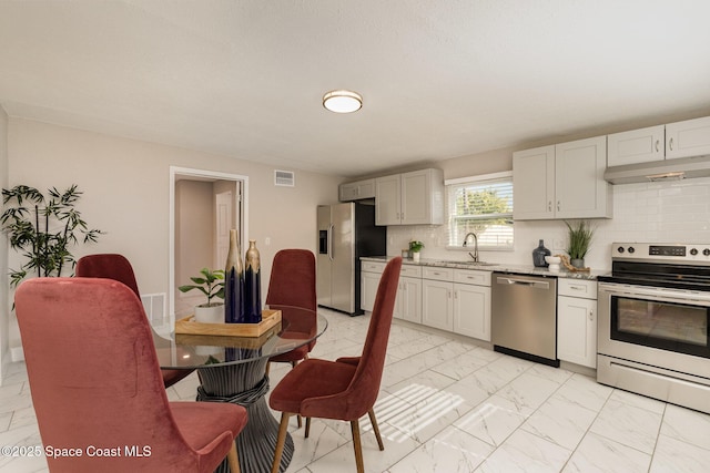 kitchen with visible vents, stainless steel appliances, marble finish floor, under cabinet range hood, and tasteful backsplash